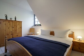 Ein Schlafzimmer mit einem hölzernen Bett, einem Nachttisch mit Lampe, einem Holzschrank und einem Fenster mit Blick.