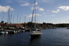Eine Marina mit mehreren Segelbooten, davon ein Segelboot im Vordergrund, und Gebäuden im Hintergrund.
