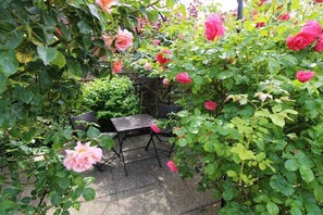 Ein Garten mit Rosenbüschen und einem kleinen Tisch im Freien.