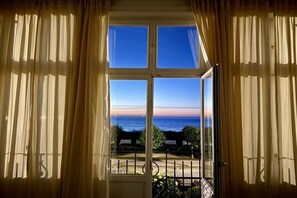 A window with curtains, a view of the ocean, and a balcony with a railing. - VILLA FORTUNA BY THE SEA, Apartment 5 (Seebad Bansin)
