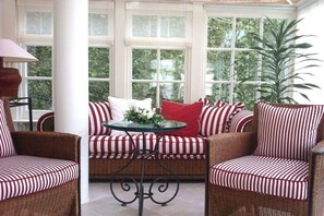 A sunroom with wicker furniture, red and white striped cushions, and a glass table. - VILLA FORTUNA BY THE SEA, Apartment 5 (Seebad Bansin)