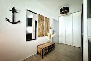 Ein Flur mit einem Holztischchen, einem Spiegel, einer Ankerdekoration und einem Kleiderschrank.