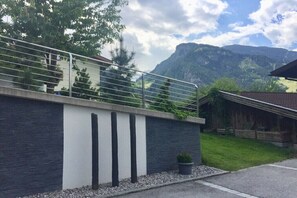 Ein modernes Gebäude mit Balkon, Bergblick und kleinem Garten.