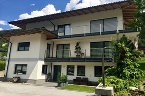 Ein zweistöckiges Gebäude mit Balkon, Blumentöpfen und einem kleinen Garten.