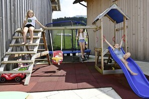 Children playing on outdoor play equipment including a slide, a swing, and a climbing structure. - Holiday apartment in Egg with swimming pool (Egg)