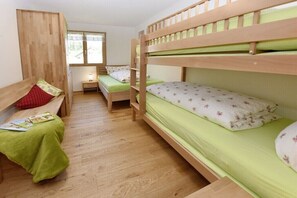 A bunk bed room with a wooden bunk bed, a single bed with a green blanket, a wooden desk, and a window with a view of the outside. - Holiday apartment in Egg with swimming pool (Egg)