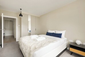 Quarto moderno com uma cama grande, uma mesa de cabeceira, um guarda-roupa e um candeeiro suspenso.