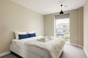 Ein Schlafzimmer mit Bett, Fenster und Blick auf Gebäude.