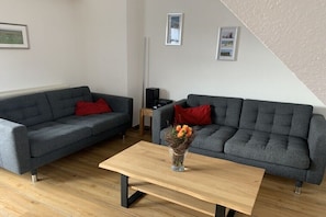 A modern living room with two grey sofas, a wooden coffee table, and a small side table with a speaker. - in the Boddenblick house, Apt. 32 (Zingst)
