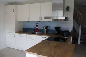 Eine moderne Küche mit weißen Schränken, einer Edelstahl-Dunstabzugshaube, einer Kaffeemaschine und einem Spülbecken.