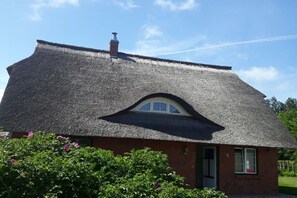 Ein traditionelles Haus mit Strohdach und kleinem Fenster.