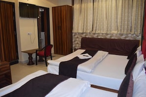Habitación de hotel con dos camas, un escritorio, una silla y zona de ducha.