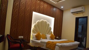 Habitación de hotel con una cama grande, una mesita pequeña, una silla y un aire acondicionado de pared.