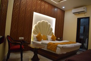 Quarto de hotel com uma cama grande, uma mesa pequena, uma cadeira e ar-condicionado fixado na parede.