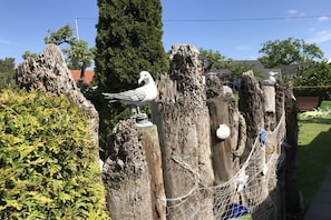 Ein Holzzaun mit einer Vogelstatue, einer Taue und einem Baum im Hintergrund.