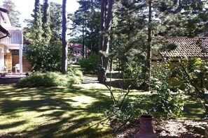 A residential property with a well-maintained lawn, tall trees, and a small garden area. - Forest settlement "Time Out" (Prerow)