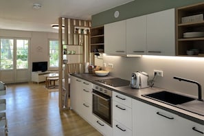 A modern kitchen with white cabinets, a built-in oven, a black countertop, and a sink. - Forest settlement "Time Out" (Prerow)