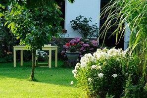 Ein Garten mit Tisch und Stühlen, einem Blumentopf und verschiedenen Blumen.