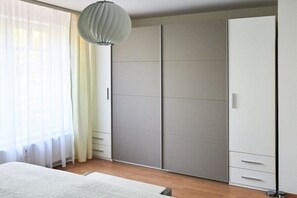 Ein Schlafzimmer mit Bett, Kleiderschrank und einer Pendelleuchte.