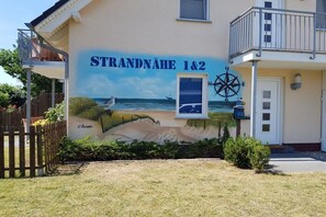 Ein Gebäude mit Wandgemälde einer Strandlandschaft und dem Text 'STRANDNAHE 1&2'.
