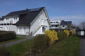 Ein zweistöckiges Wohngebäude mit Treppe, Balkon und Solaranlage auf dem Dach.