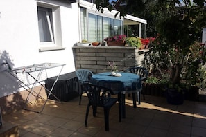 Eine Terrasse mit Tisch, Stühlen, einer Wäscheleine und Topfpflanzen.