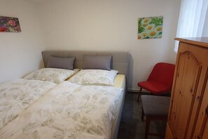 Ein Schlafzimmer mit einem Bett, einem roten Sessel und einem Holzschrank.