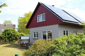 Ein zweistöckiges Haus mit roter Fassade und einer Solaranlage auf dem Dach.