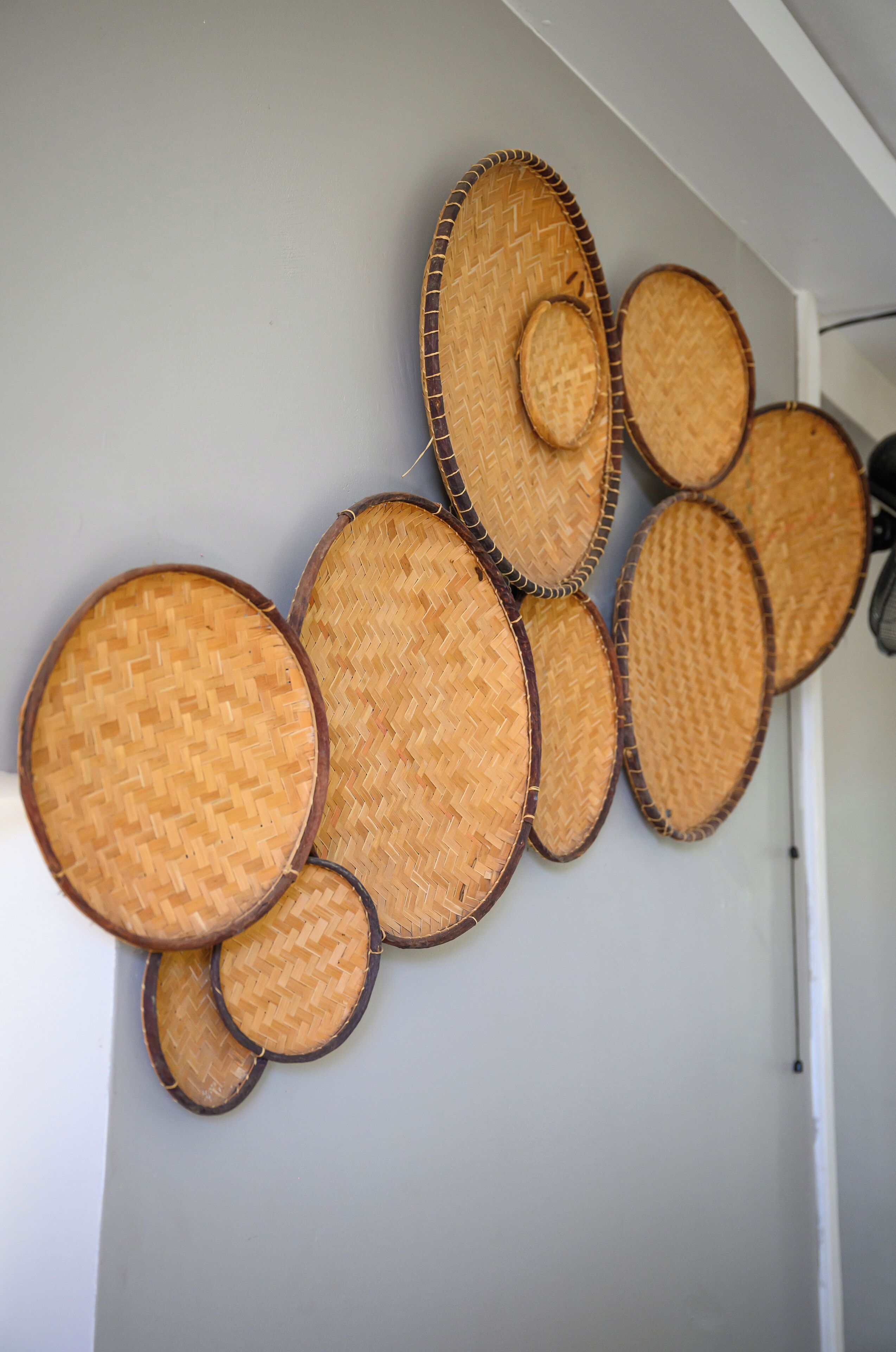 Eine Wand mit runden, gewebten Körben unterschiedlicher Größe.