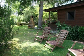Eine Holzhütte mit Veranda, Sitzgelegenheit im Freien und Schornstein.