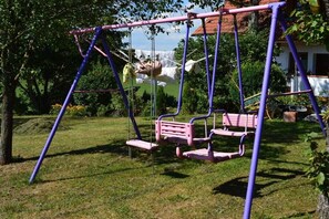 Ein Schaukelstuhl in einem Garten, im Hintergrund ein Haus.