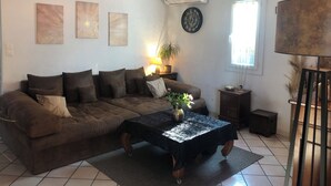 Ein Wohnzimmer mit braunem Sofa, Couchtisch, Lampe und Wandbildern.