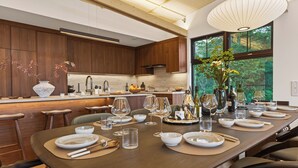 A modern kitchen with wooden cabinets, a large island with bar stools, and a dining area set for a meal.