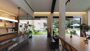 A modern reception area with a stone counter, wooden seating, and large windows offering a view of a garden.
