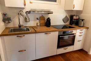 A compact kitchen with a sink, stove, and oven, wooden countertops, and white cabinetry. - Holiday apartment with 2 bedrooms (Unteruhldingen)