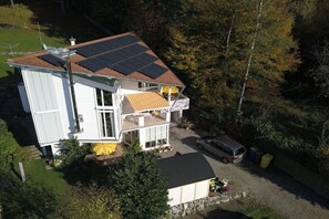 A two-story house with solar panels on the roof, a covered patio, and a car parked in the driveway. - Holiday apartment with 2 bedrooms (Unteruhldingen)
