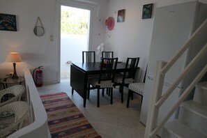 A dining area with a table and chairs, a fire extinguisher, a lamp, and a colorful rug. - Charming Naxos Villa, Ocean Views, Modern Comfort, Tranquil Escape (Naxos)