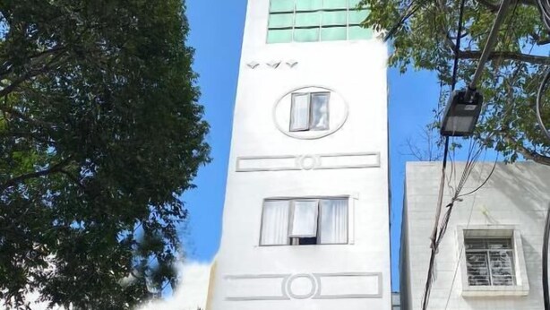 Un edificio de varios pisos con un diseño vertical llamativo, que incluye un gran ventanal y una puerta.