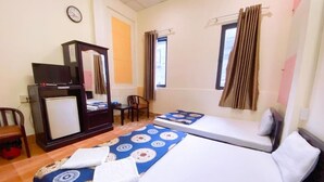 Habitación de hotel con dos camas, un escritorio con computadora, una silla, un espejo y una ventana con cortinas.