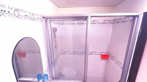 Un baño pequeño con lavamanos, espejo y cabina de ducha.