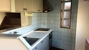A kitchen with a gas stove, sink, cabinets, and a window.