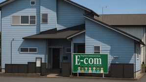A two-story building with a blue exterior, a front entrance, and a signboard advertising English communication services.