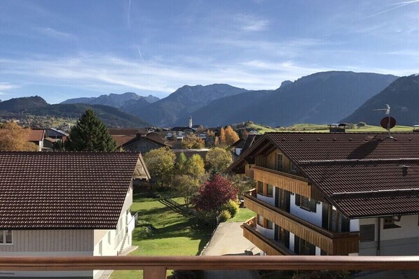 Ein Wohngebiet mit traditioneller Architektur, einem klaren Himmel und Bergen im Hintergrund.