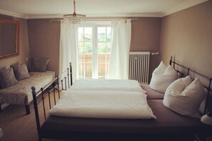 Une chambre à coucher avec un lit, un canapé, un radiateur et une fenêtre avec des rideaux.