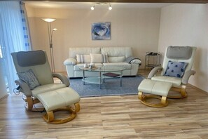 Ein Wohnzimmer mit einer Couch, zwei Schaukelstühlen, einem Couchtisch und einer Stehlampe.