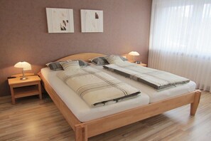 Ein Doppelbett mit Holzrahmen, zwei Nachttische mit Lampen und ein Kunstwerk an der Wand.