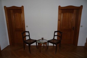 Une pièce avec deux portes en bois, une petite table avec des chaises et un verre d’eau.