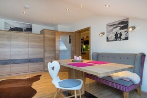 Ein modernes Interieur mit einem Holzespeisetisch, einem grauen Sofa und einem Cowhide-Teppich.