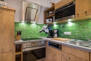 Eine Küche mit grüner Marmorfliesenspiegel, Holzschränken und Edelstahlgeräten, sowie einer Hundefigur auf der Arbeitsplatte.