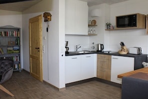 A compact kitchen with white cabinets, a microwave, a toaster, and a coffee maker. - Holiday apartment with 1 bedroom (Todtnauberg \/ Schwarzwald)
